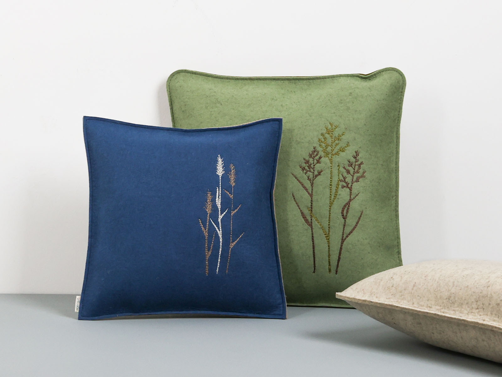 Sofakissen aus Filz in ozean blau und salbei grün bestickt mit Motiv Gräser